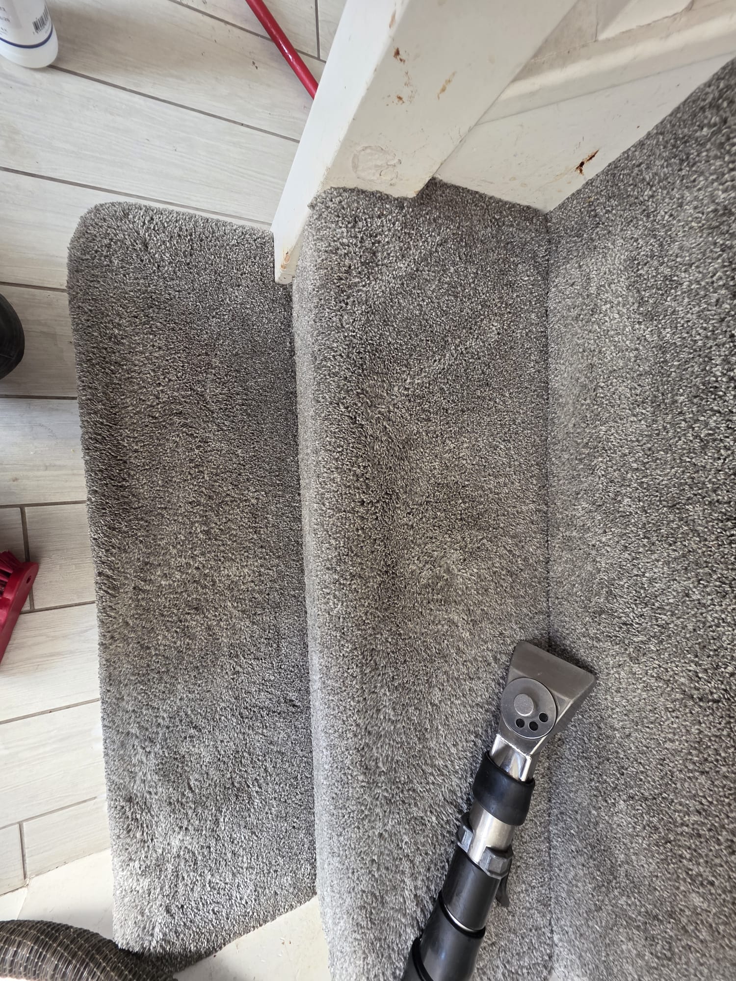 Grey carpet stairs being cleaned with professional extraction wand visible
